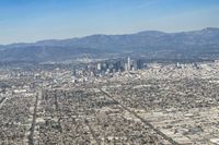 cityscape in front of mountain range from the sky and plane wing view on clear day