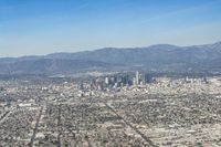 cityscape in front of mountain range from the sky and plane wing view on clear day