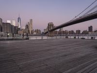 a park bench and benches on the boardwalk with a view of the city skyline and bridge