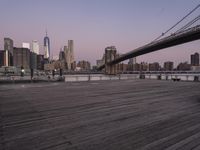 a park bench and benches on the boardwalk with a view of the city skyline and bridge