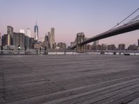 a park bench and benches on the boardwalk with a view of the city skyline and bridge