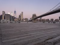 a park bench and benches on the boardwalk with a view of the city skyline and bridge