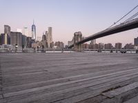 a park bench and benches on the boardwalk with a view of the city skyline and bridge