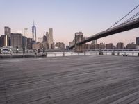 a park bench and benches on the boardwalk with a view of the city skyline and bridge