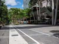 an image of a street that is surrounded by trees and buildings in the background there are two trees next to the road