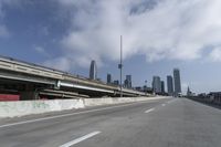 a view of city from inside of a vehicle in a moving blurry picture, including the roof of the vehicle and a sign on the side of the freeway that reads under