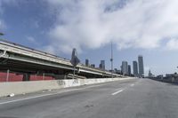 a view of city from inside of a vehicle in a moving blurry picture, including the roof of the vehicle and a sign on the side of the freeway that reads under