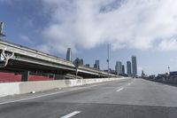 a view of city from inside of a vehicle in a moving blurry picture, including the roof of the vehicle and a sign on the side of the freeway that reads under