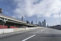 a view of city from inside of a vehicle in a moving blurry picture, including the roof of the vehicle and a sign on the side of the freeway that reads under