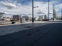 there is a bench on this sidewalk by the water next to buildings and boats in the background