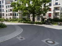 a paved area with a clock in the middle of it and lots of trees around it