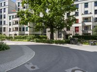 a paved area with a clock in the middle of it and lots of trees around it