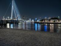 a bench by the water in the city at night time, with buildings reflecting in the water