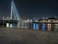 a bench by the water in the city at night time, with buildings reflecting in the water