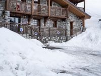 there is a bunch of snow piled on the ground outside of a house in the mountains