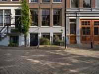 three brick buildings and two wooden doors are in front of a large brick walkway in a square setting