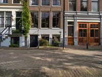 three brick buildings and two wooden doors are in front of a large brick walkway in a square setting