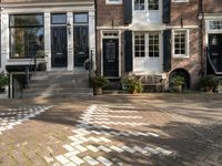 a black and white checkered pavement that is outside a building, with blue shutters