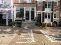 a black and white checkered pavement that is outside a building, with blue shutters