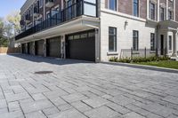 a brick walkway leads to garages and a covered walkway leading into the apartment building