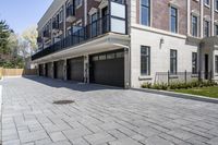 a brick walkway leads to garages and a covered walkway leading into the apartment building