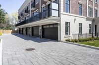 a brick walkway leads to garages and a covered walkway leading into the apartment building