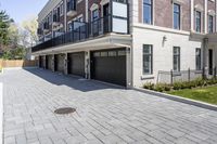 a brick walkway leads to garages and a covered walkway leading into the apartment building