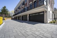 a brick walkway leads to garages and a covered walkway leading into the apartment building