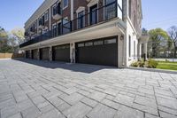 a brick walkway leads to garages and a covered walkway leading into the apartment building