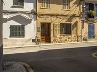 there is an old building with blue shutters and wooden door on it next to the sidewalk