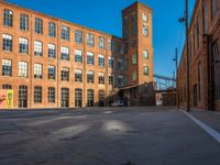 the empty parking lot is filled with many windows of a large brick building with multiple floors