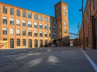 the empty parking lot is filled with many windows of a large brick building with multiple floors