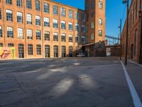 the empty parking lot is filled with many windows of a large brick building with multiple floors