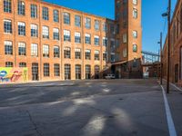 the empty parking lot is filled with many windows of a large brick building with multiple floors