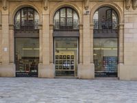 there is a woman sitting on a bench by the window of a building looking in to a book store