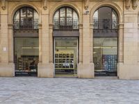 there is a woman sitting on a bench by the window of a building looking in to a book store