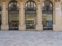 there is a woman sitting on a bench by the window of a building looking in to a book store