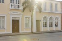 there is a yellow building with palm trees on it in front of the entrance and a black car on the street