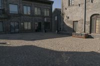 the person is walking down the street near old buildings on a sunny day with a red umbrella