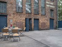 an old brick building with chairs in front and tables outside of the building next to the doorway