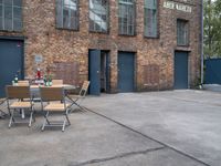 an old brick building with chairs in front and tables outside of the building next to the doorway