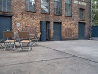 an old brick building with chairs in front and tables outside of the building next to the doorway