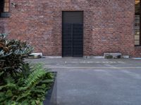 a black door that is sitting on a building next to plants in front of the window