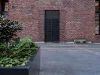 a black door that is sitting on a building next to plants in front of the window