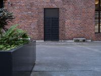 a black door that is sitting on a building next to plants in front of the window