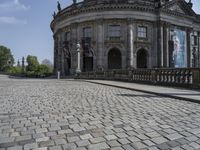 the large stone building is in front of the trees and bushes area of the park