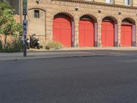 the man stands in front of an old building, while a motorcycle is driving by