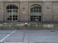 a fire hydrant next to an empty parking spot near building's windows with window treatments