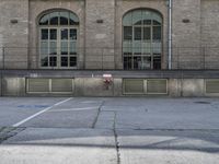 a fire hydrant next to an empty parking spot near building's windows with window treatments