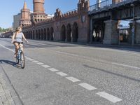 a person walking down a road next to a building and a bridge on a sunny day